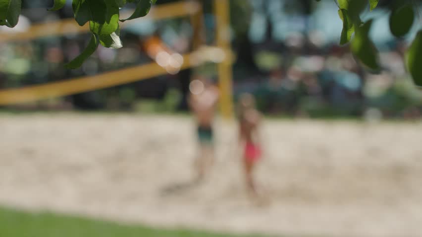 young people playing beach volleyball near lake in summer