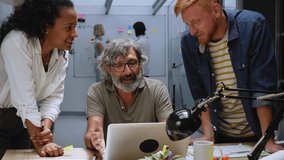 Diverse group of co-workers gathered together chatting happy with male leader about new strategies. Business people look at and point to laptop present marketing ideas to improve financial project - Powered by Shutterstock - Get 15% off with code: PIKWIZARD15