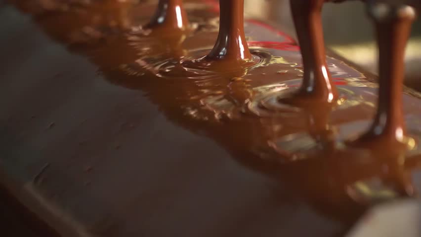 Conveyor with liquid chocolate. Confectionery factory. Chocolate factory. Candy production.