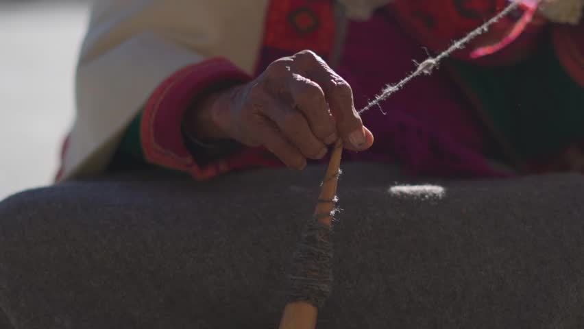 A happy grandmother spinning wool in an interior village of Himachal Pradesh . Making yarn out of wool. Lady wearing traditional wool dress and traditional ornaments. Royalty-Free Stock Footage #3424396007
