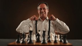 Mature chess master with a warm smile stands ready at the chessboard, embodying strategy and anticipation in the quiet before the strategic duel unfolds. Camera 8K RAW. - Powered by Shutterstock - Get 15% off with code: PIKWIZARD15