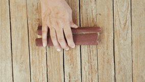 Craftsman's hand polishing a wooden board with sandpaper. shot hand of carpenter or joiner sanding wooden plank with sanding paper.4k video