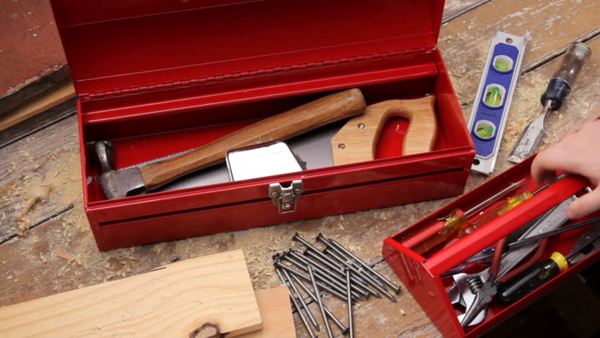 Red tool box. Carpenter takes puts red tool box on workbench, open and takes out