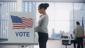 Young African American Woman Filling Out a Ballot Next to a Voting Booth on the Day of Elections in the United States. Diverse Men and Women Voting for Presidential Candidates in a Polling Station - Powered by Shutterstock - Get 15% off with code: PIKWIZARD15