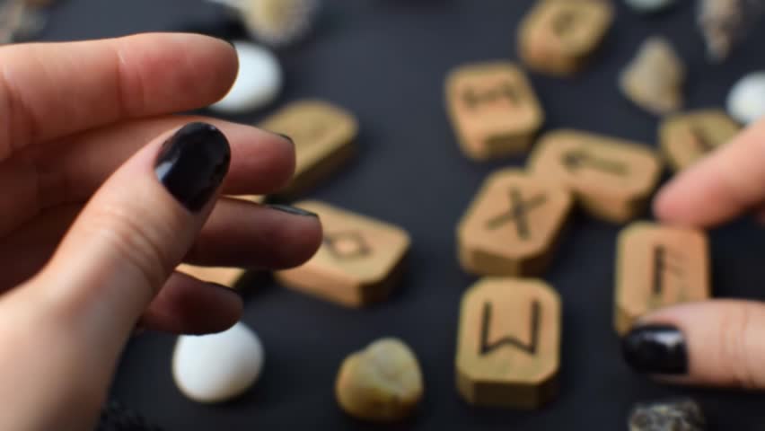 Wooden runes in hand on black table background. Scandinavian magical esoteric symbols and signs for divination and prediction of the future and destiny, esotericism concept.