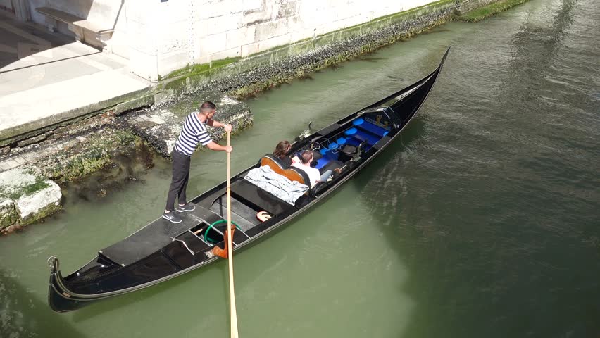A touristic gondola rides through the water filled streets of Venice, Italy.