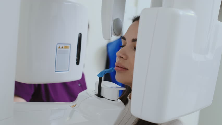 Woman patient bites in mouth bite block under guidance of dental assistant for X-ray procedure. Patient undergoes dental checkup in clinic