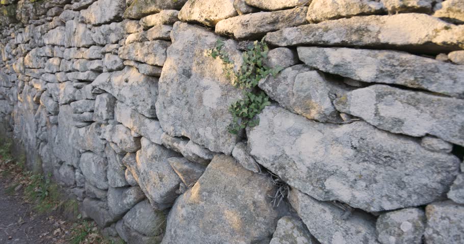 Walking on medieval road with abandoned stone walls with green vegetationin Allariz in Galicia Spain  at sunset 