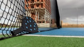 video of pickleball ball and paddles resting on the net of a pickleball court