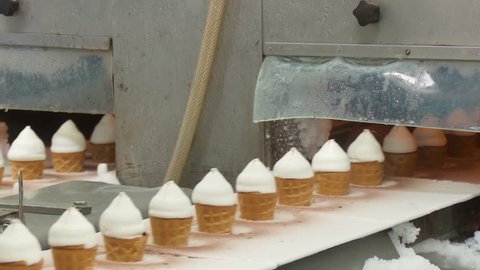 Ice cream in a cone. Filling of wafer cups with ice cream. Ice cream production line. Vanilla ice cream.