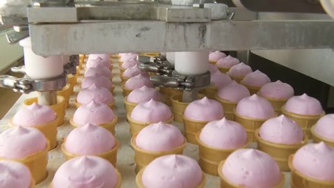 Ice cream factory. Filling of wafer cups with ice cream. Pink fruity and vanilla ice cream in a waffle cup. Automated production of ice cream.