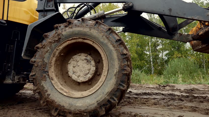 tractor riding on ground on construction site in modern cottage complex, details view of wheels Royalty-Free Stock Footage #3424952237
