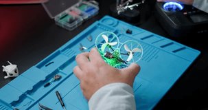 Test flight of the FPV drone after repair. A close-up of the hands of an engineer who repairs drones and checks his work. A young man is engaged in his hobby at home in the evening.