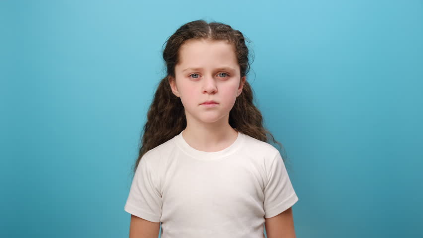 Portrait of upset little girl child standing with grimace of pain, touching sore sprained wrist, health problem, wearing white casual t-shirt, posing isolated over blue color background wall in studio Royalty-Free Stock Footage #3424992167