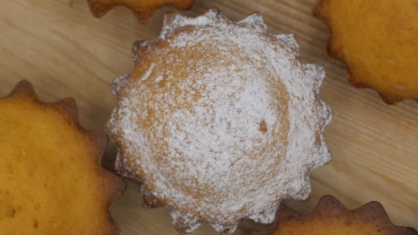 Top view of Spinning cupcakes with powdered sugar on the wooden tray