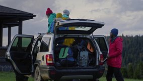Diverse group of tourists arrive to rental house in forest on car. African American man talks with friends, takes backpack from trunk and gives to teenager. Hikers during trip or trek to mountains. - Powered by Shutterstock - Get 15% off with code: PIKWIZARD15