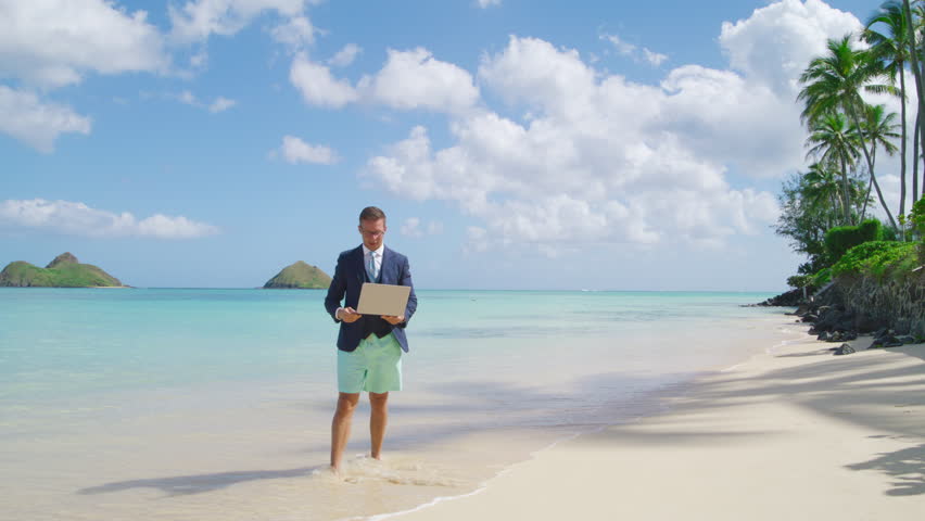 An ecstatic businessman in semi-formal attire jumps in the air, holding a laptop, on a tropical beach with palm trees and clear blue sky. Slow Motion, 4K Hi Quality.  Royalty-Free Stock Footage #3425006183