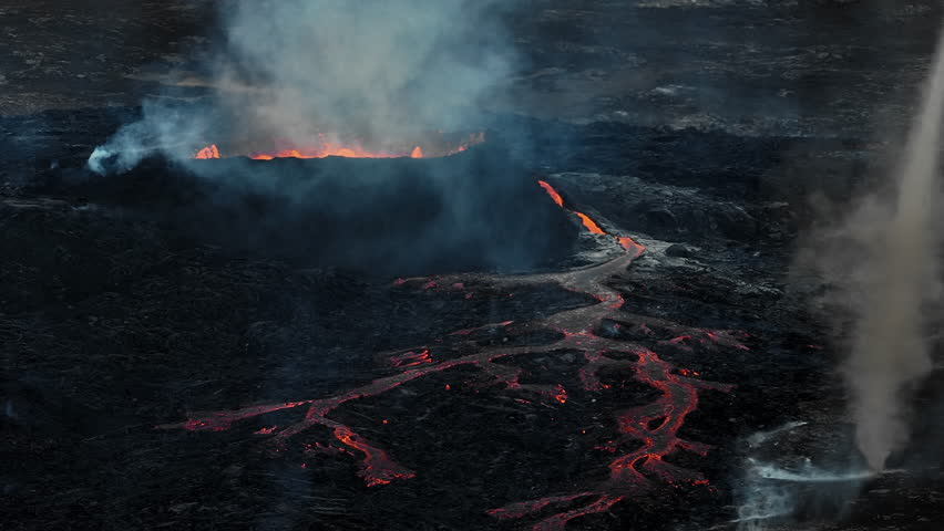 Volcano eruption in Iceland, summit crater, gas expulsion, and molten lava spilling out from a vent, aerial side view. Natural hazard and geothermal energy concepts. Royalty-Free Stock Footage #3425105259