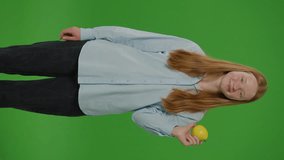 Split Green Screen. Vertical Video Teenage Girl Smiles As She Eats An Apple, Embodying. Healthy Eating And School Nutrition. A Vivid Depiction Of Youth Embracing Nutritious Choices In Their Daily Diet