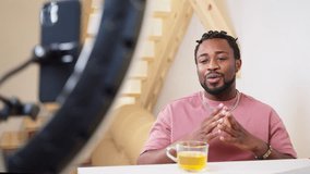 positive black man streaming in social media, speaking to followers through smartphone, blogger and influencer portrait in home studio, lifestyle blogger creating content