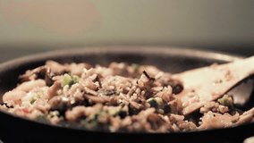 Steam coming out of freshly cooked fried rice dish in a pan. Home chef is mixing the food with wooden spatula at the end of the clip.