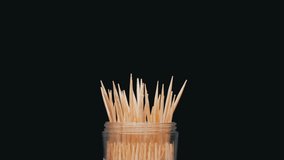 Wooden Toothpicks Rotate on a Black Background. Close up. A set of bamboo toothpicks in a transparent plastic cup. Home oral care after meals. Teeth cleaning. Blurred motion. Dentistry concept. Loop. - Powered by Shutterstock - Get 15% off with code: PIKWIZARD15