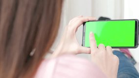 woman take cell phone with green screen in the home
