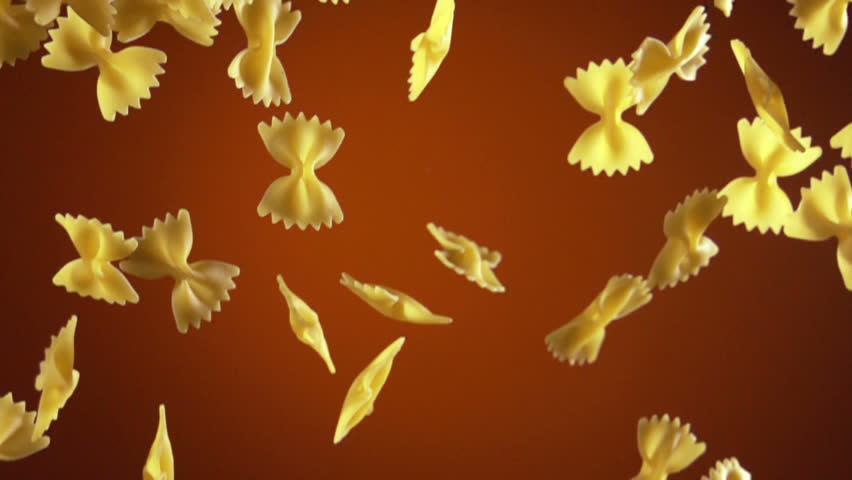 Farfalle pasta flow with slow motion over dark orange background
