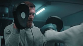 Close up of female fighter in boxing gloves practicing fighting technique and training with male coach in gym. Woman hits punching mitts on boxing ring. Physical activity and intensive workout. - Powered by Shutterstock - Get 15% off with code: PIKWIZARD15