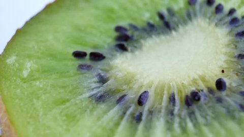 Juicy kiwi rotates as background. Macro of slice of fresh kiwi fruit isolated