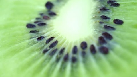 Slice of fresh kiwi fruit isolated. Macro of juicy kiwi rotates as background.