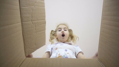 A little girl looks in the box, is surprised and happy to receive a surprise. The child opened a box with a gift. Slow Motion