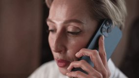 Close-up face of serious middle-aged business woman having work call in office using mobile phone. Elegant mature female entrepreneur with gray hair talking on smartphone. Shooting in slow motion. - Powered by Shutterstock - Get 15% off with code: PIKWIZARD15