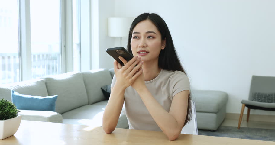 Serious young Asian smartphone user woman recording voice audio message on smartphone, talking on cellphone speaker, speaking at mobile phone, finishing conversation, using gadget for communication Royalty-Free Stock Footage #3425708679