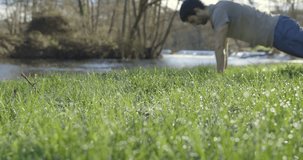 Out of focus video of young skinny man doing pushups in grass on a bright sunny day