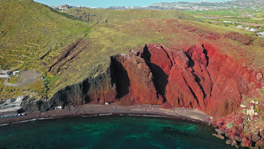 Aerial view of Red beach in Santorini surrounded by red hills and volcanic rocks. Rock formations with volcanic rocks, red pebbles, and sand of various colours, marine life for snorkelling lovers.