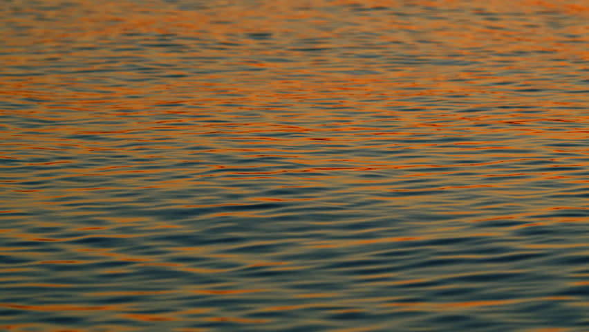 Water In Ocean With Sunset Reflected On Waves. View Of Calm Waves. Abstract Nature Background. Slow motion.