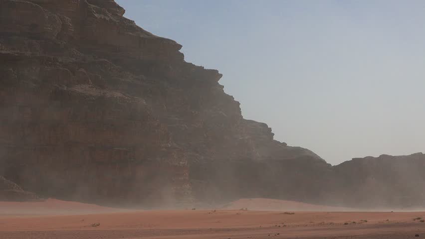 Desert Sandstorm. Sand waving in the wind in dunes in desert. Wadi Rum desert. Valley of the Moon. Panorama of large rock formations. Extreme weather.