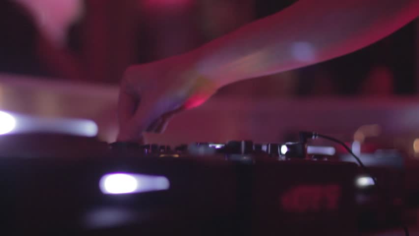 DJ in headphones is performing in night club
