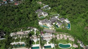 Backward reveal drone footage of luxury seaside villas on sunny day. Manggis Bay, Bali, Indonesia.