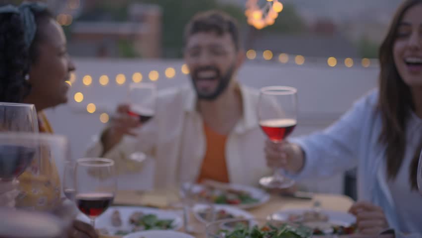 Gathering of cheerful young friends toasting with red wine and celebrating party on terrace of house. People together drinking alcoholic beverages outdoor. Boys and girls enjoying free time on weekend Royalty-Free Stock Footage #3426065209