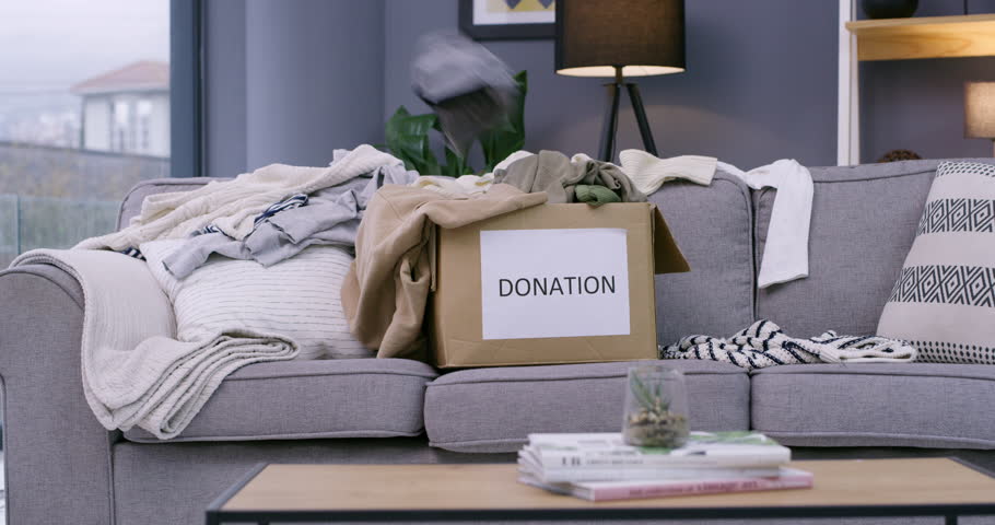 Box, donation and clothes for community service or social responsibility, non profit or charity. Fashion, package and sofa in living room for support project or outreach program, organization or help Royalty-Free Stock Footage #3426205371