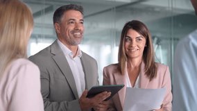 Busy business team people discussing work standing in office. Smiling mature business man and business woman professional corporate executive leaders managers having conversation with team. - Powered by Shutterstock - Get 15% off with code: PIKWIZARD15