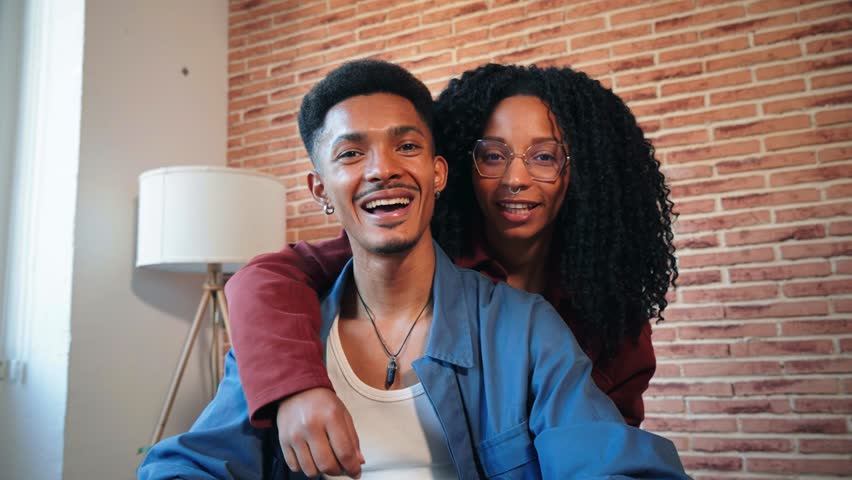 Young african american couple showing keys of their first house after purchase and moving to new home together. happy husband and wife hugging in their apartment excited to be owners of a apartment