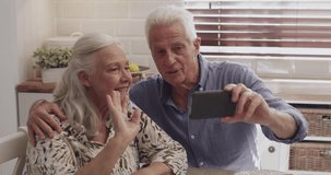 Home, video call and elderly couple with a cellphone, connection and breakfast with internet, speaking and contact. Apartment, old man or mature woman with a smartphone, online chat or digital app