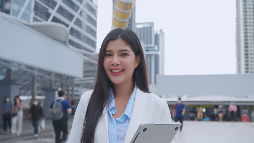 Portrait of Asian youg beautiful businesswoman standing outdoor in city. Attractive employee girl worker feel happy and confident then smile, looking at camera. Job application and recruitment concept