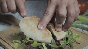 Chacarero front video showing expert hands cutting with a knife on a wooden cutting board. Cross-sectional view of the sandwich. Typical Chilean food and drink