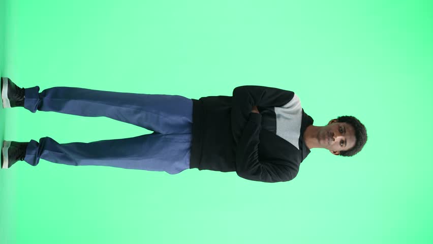 A man, full-length, on a green background, crossed his arms