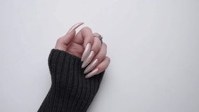 Beautiful hands of a young woman with pearl colored  manicure on nails against white background. 