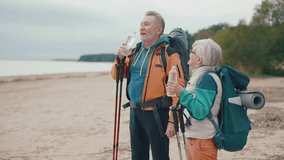 Senior happy family couple travel drinking water admiring nature sitting having break on stones. Hikers old man woman resting cuddling enjoy outdoors activity. Hiking and travel adventure concept. - Powered by Shutterstock - Get 15% off with code: PIKWIZARD15